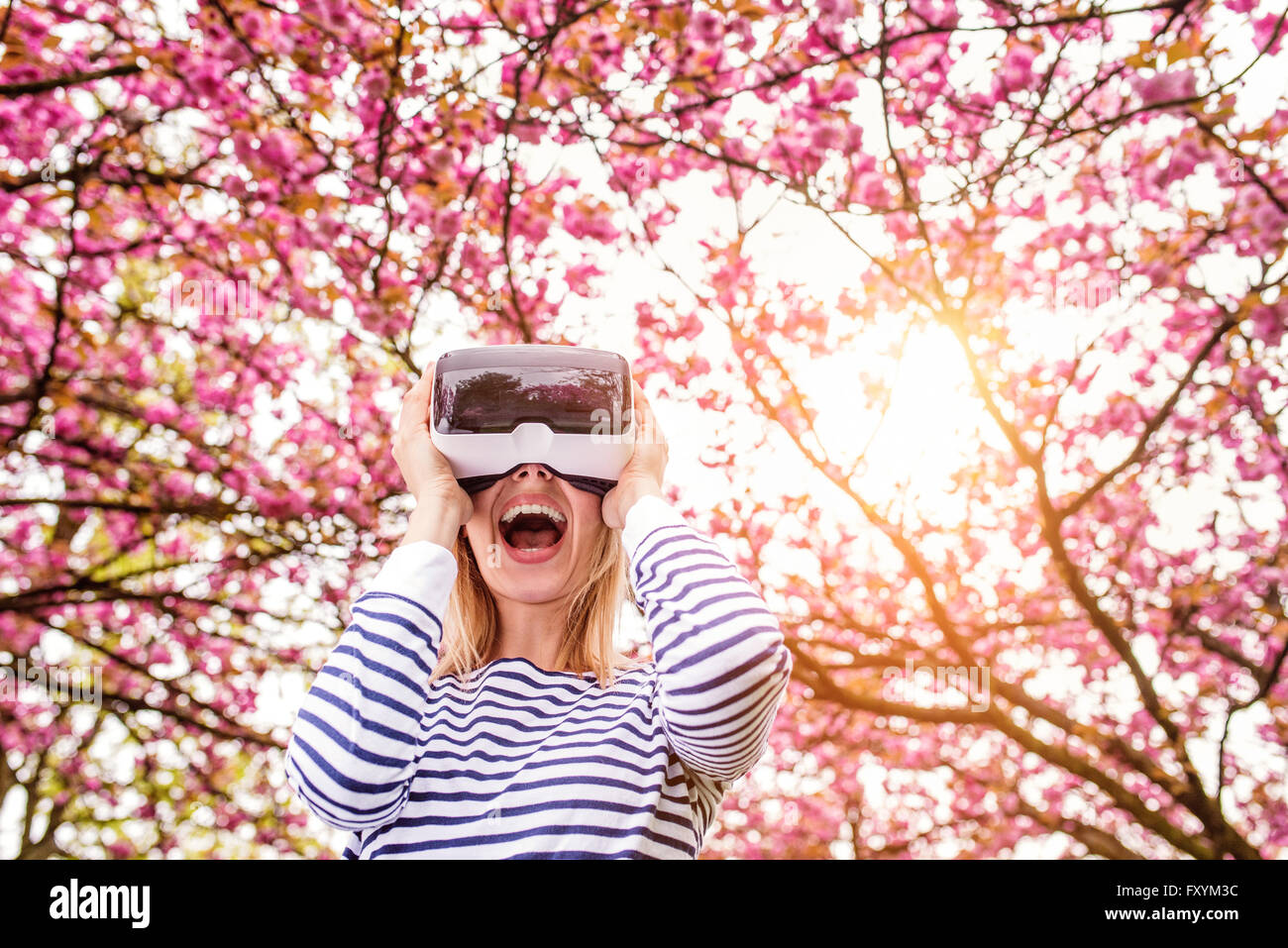 Woman wearing virtual reality goggles outside in spring nature Stock Photo