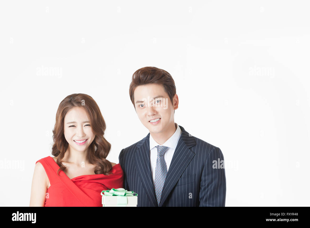 Portrait of young smiling couple with present box staring at front Stock Photo