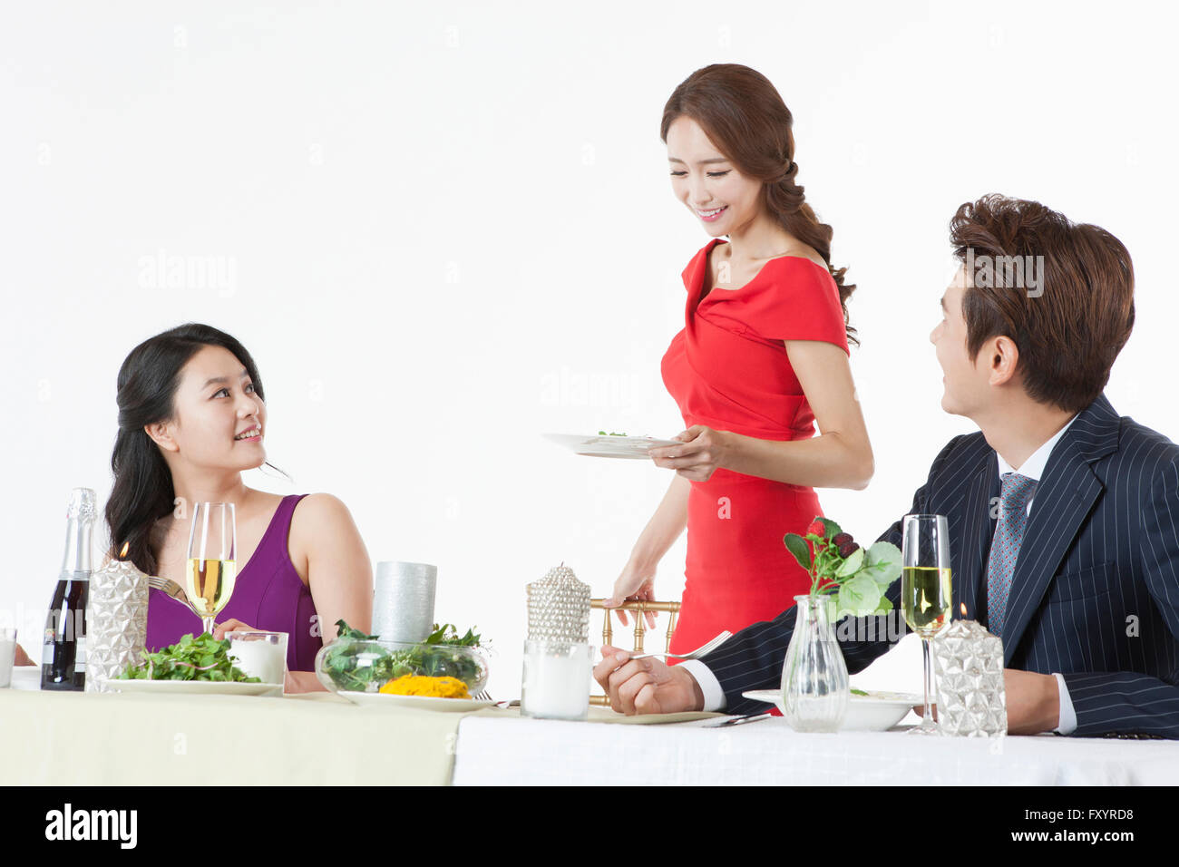 Portrait of three young smiling people having meals at party Stock Photo