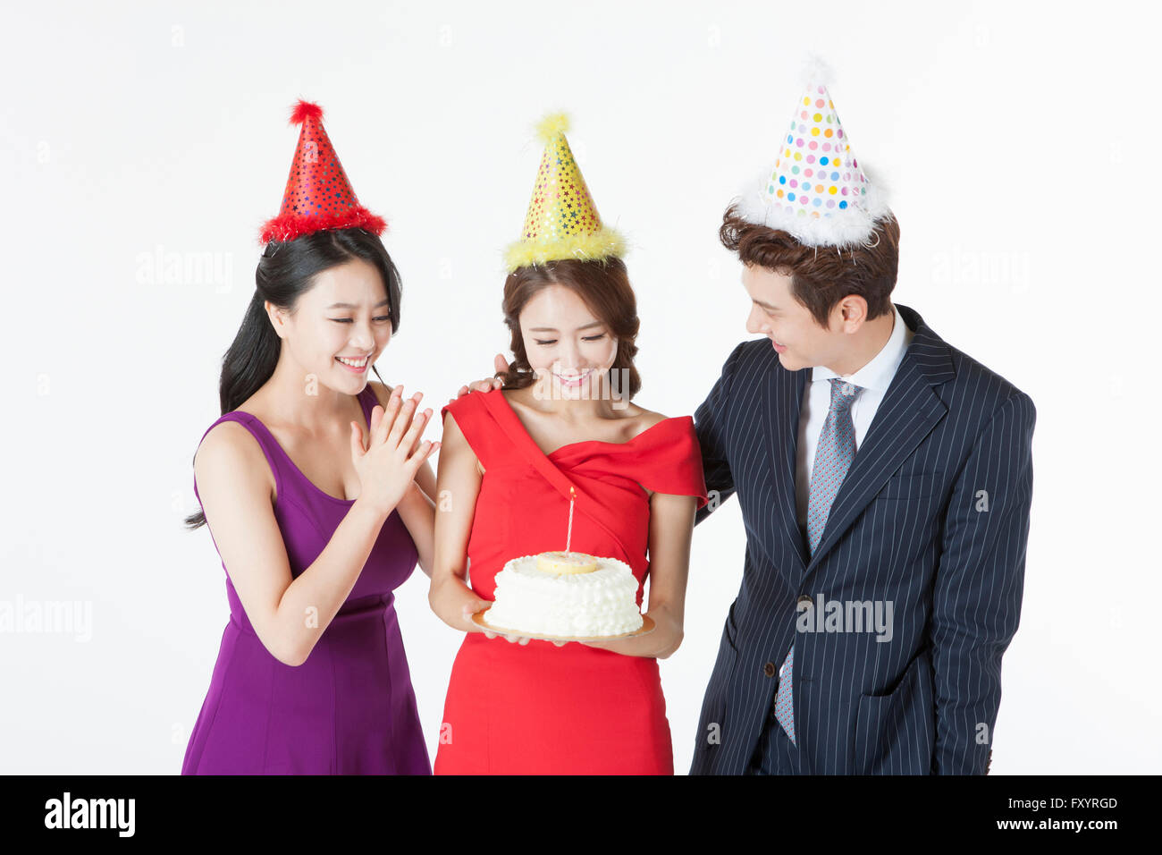 Portrait of three young people with a cake looking down Stock Photo
