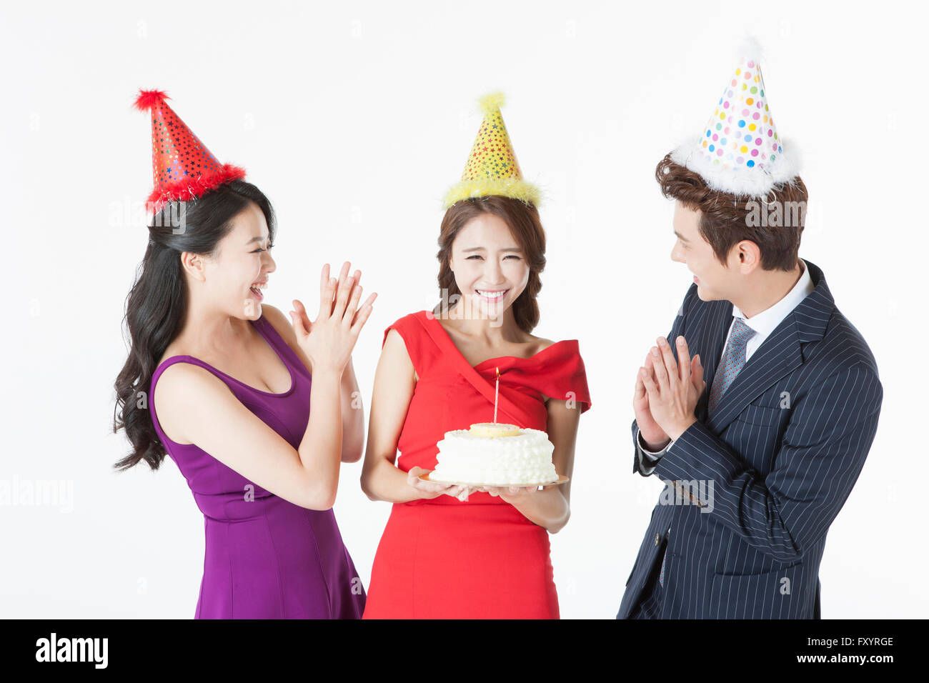 Portrait of young smiling woman with a cake and her friends clapping hands Stock Photo