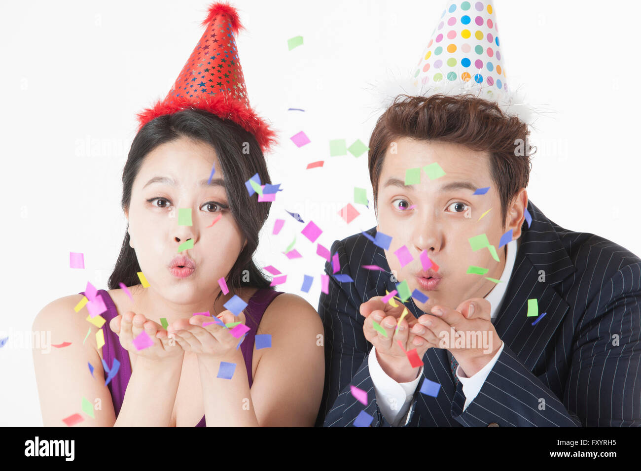 Portrait of young woman and a young man blowing confetti Stock Photo
