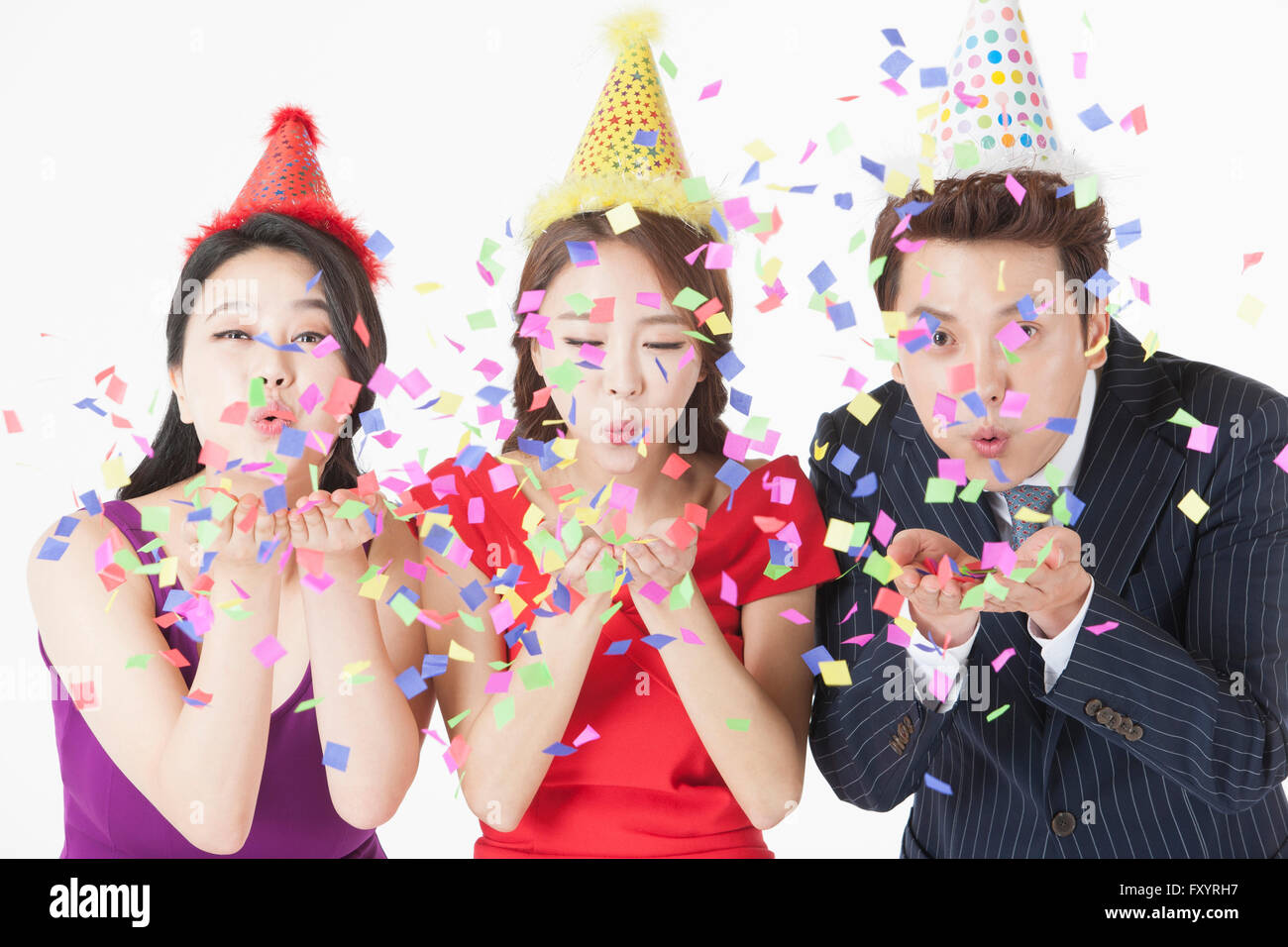 Portrait of three young people blowing confetti Stock Photo