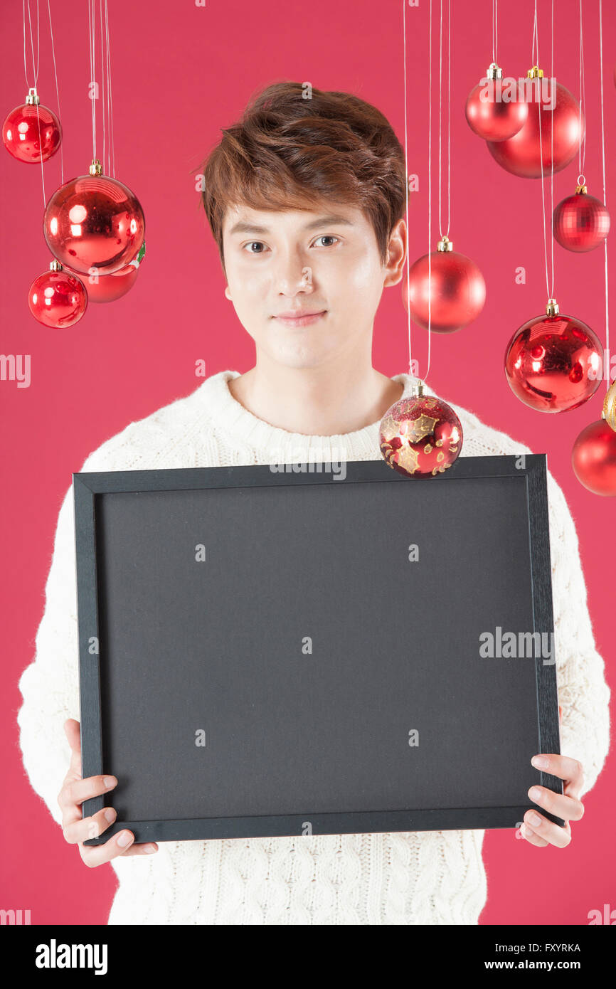 Portrait of smiling man in his early thirties showing a frame with Christmas balls Stock Photo
