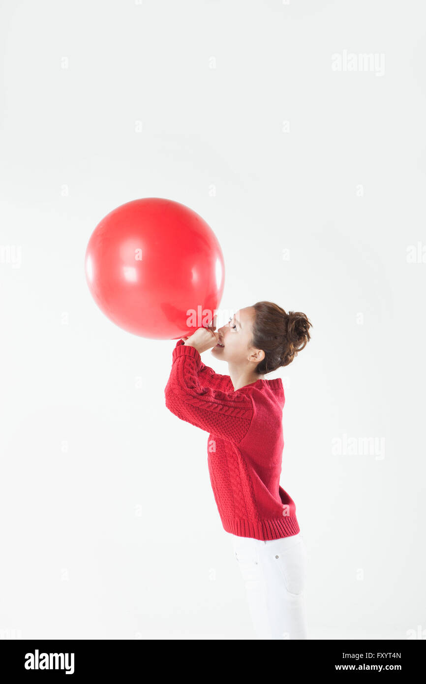 Side view of young smiling woman blowing a balloon Stock Photo