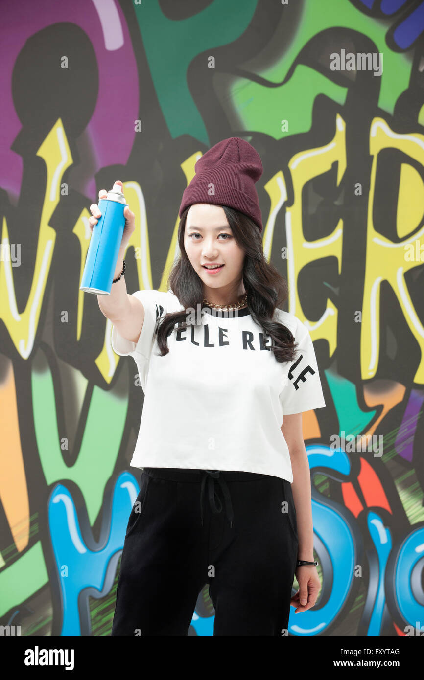 Young woman in hip-hop style holding a spray against graffiti art Stock Photo
