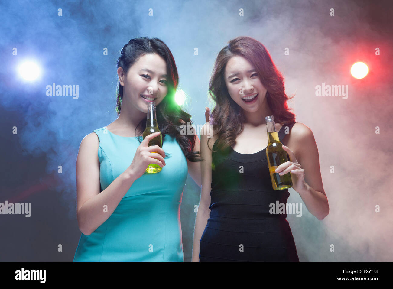 Portrait of two young smiling women holding beer bottles staring at ...