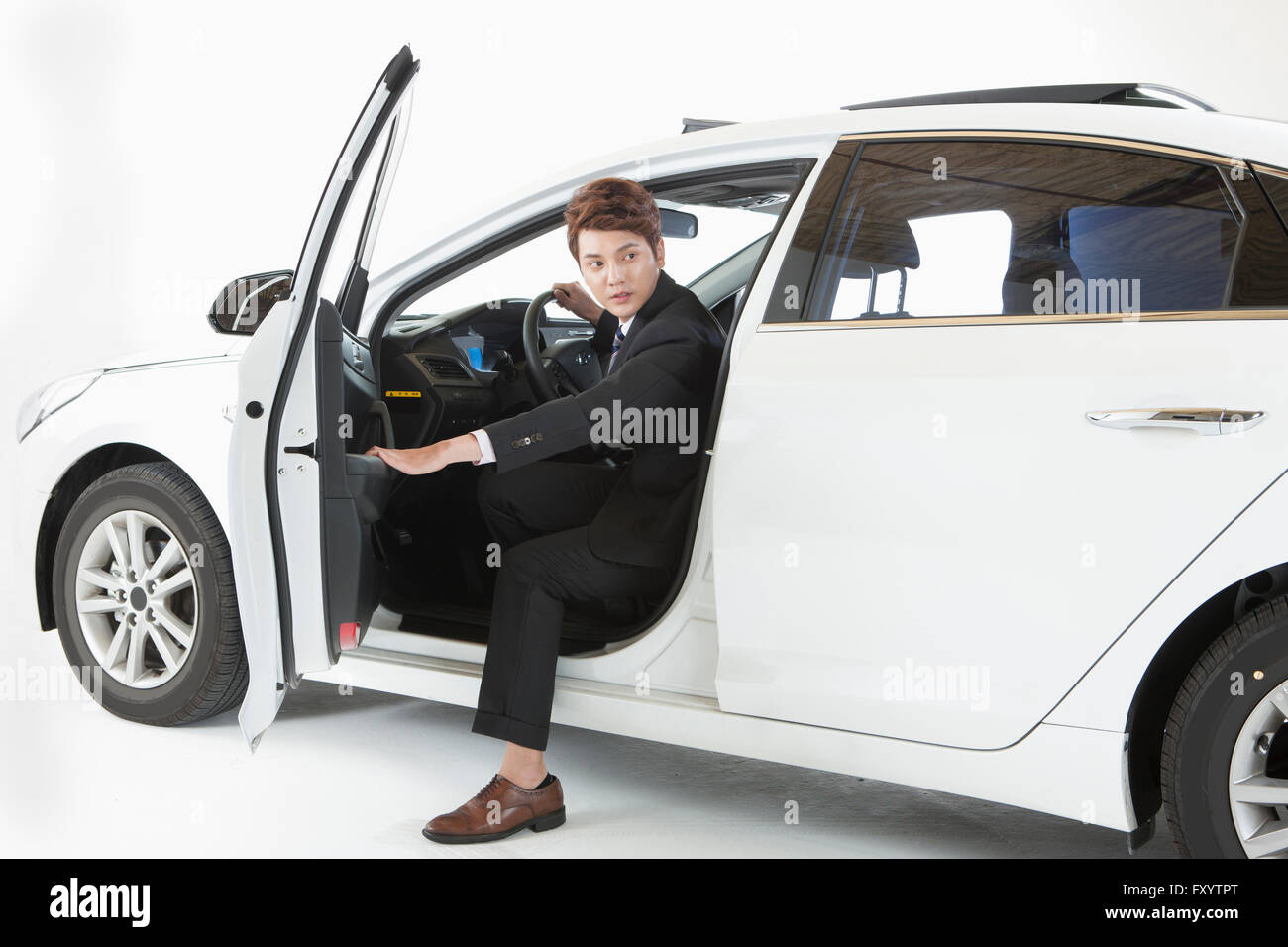 Young man in his early thirties in suit getting off a car Stock Photo