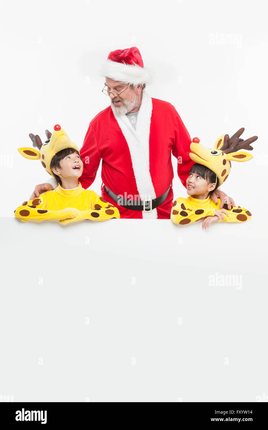 Portrait of boy and gril dressed like deer with smiling Santa Claus Stock Photo