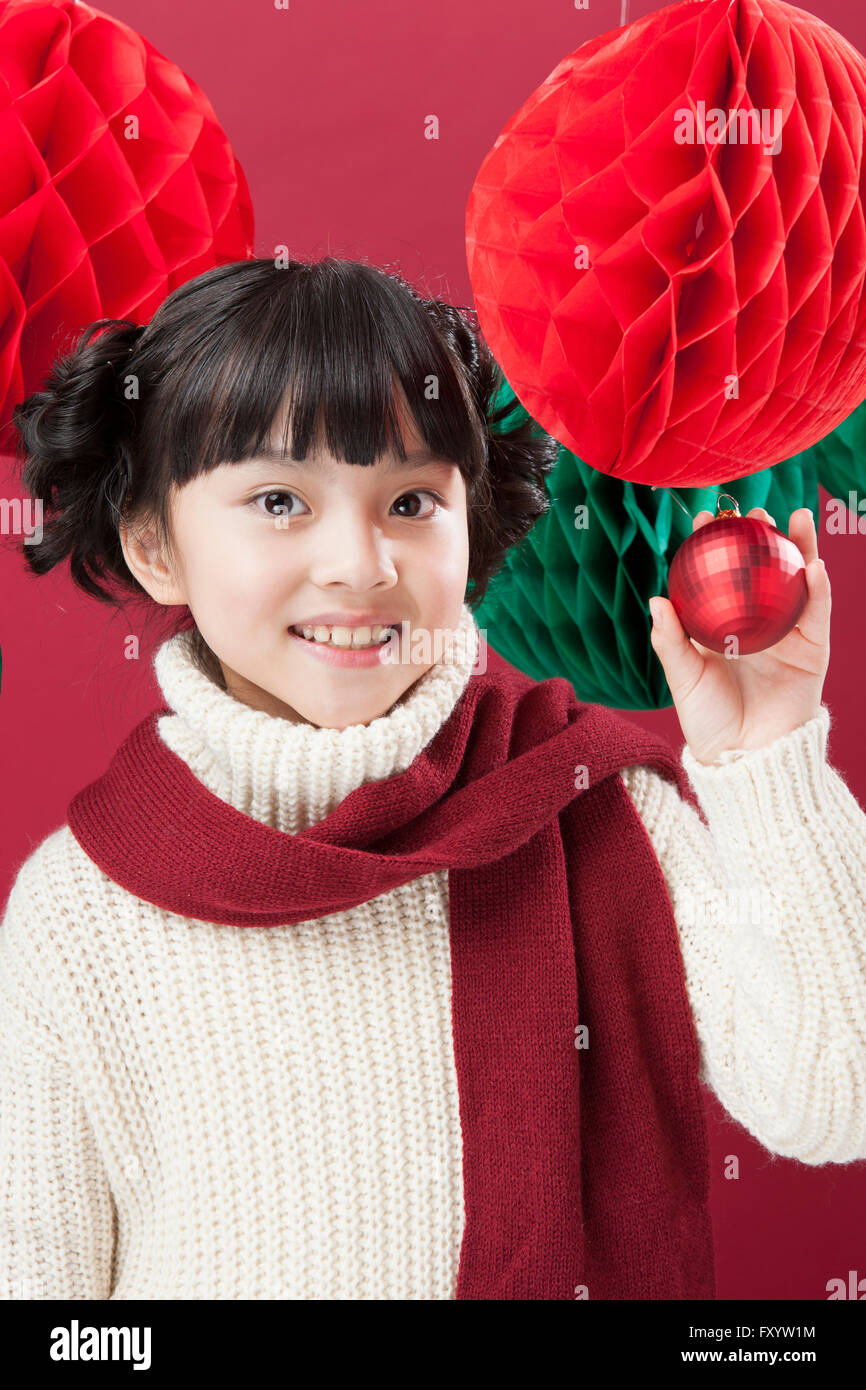 Portrait of smiling girl holding Christmas ball saring at front Stock Photo