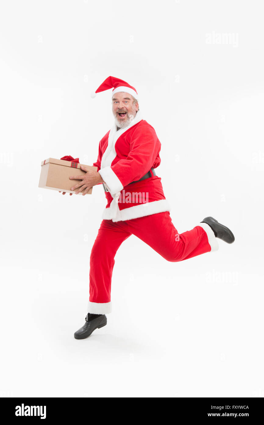 Smiling Santa running with present box staring at front Stock Photo