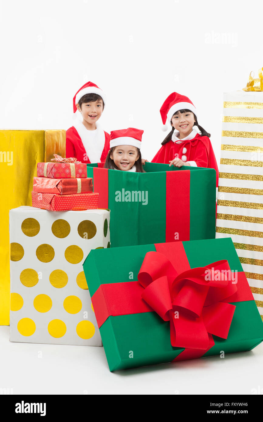 Boy and girl posing with a girl in a big present box staring at front with smiles Stock Photo