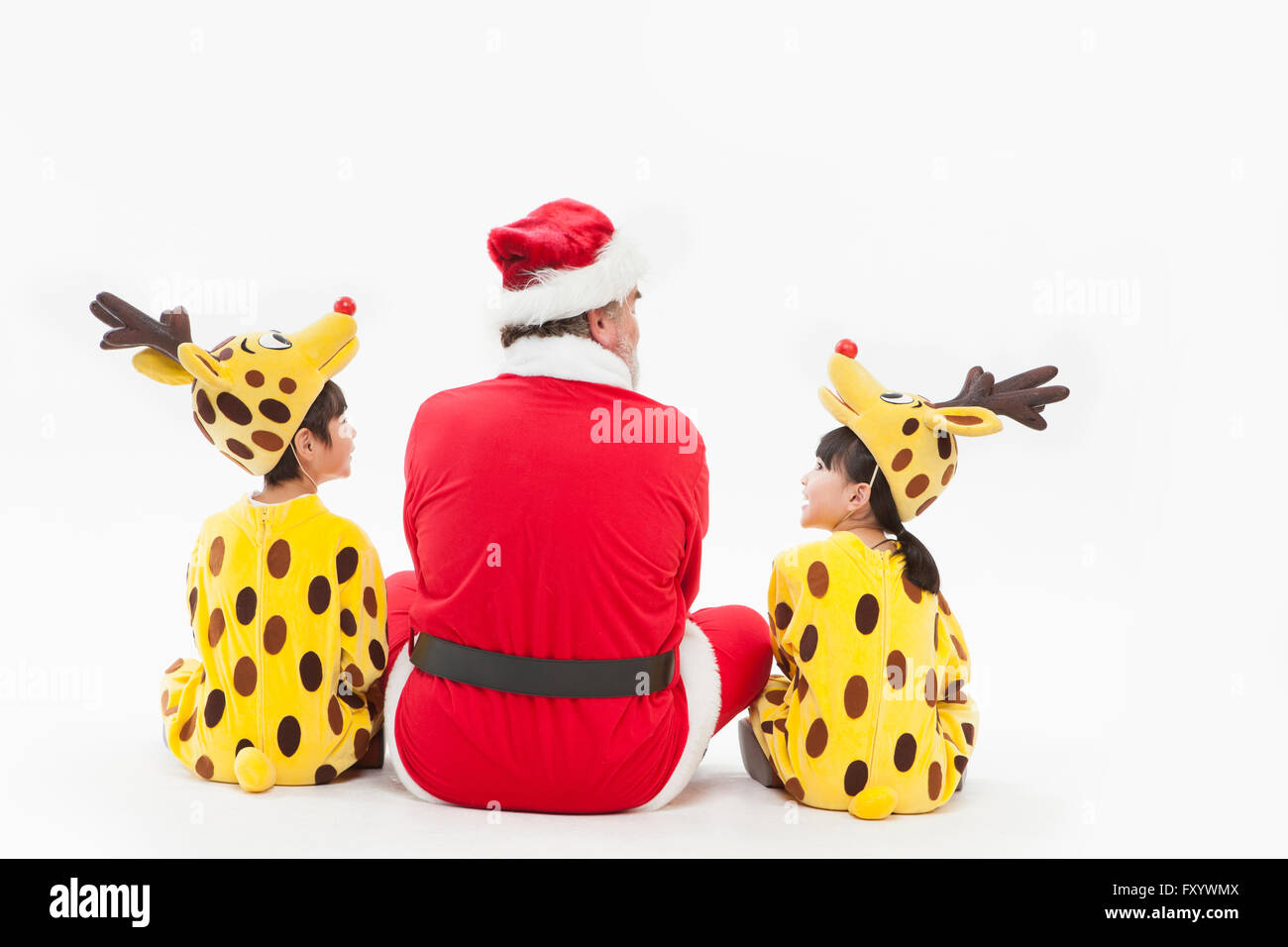 Back of children dressed like reindeer and Santa sitting face to face Stock Photo