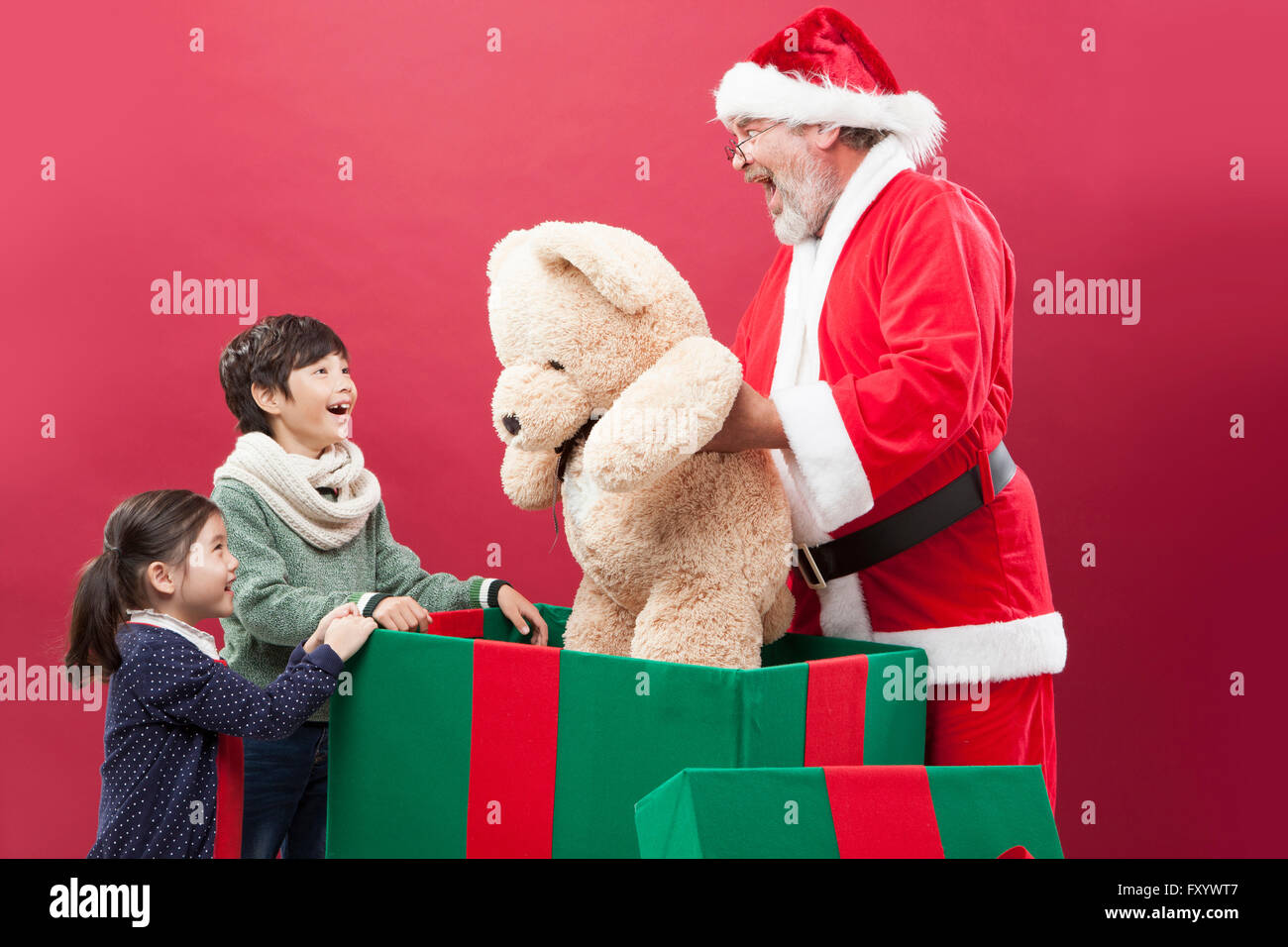 Side view of smiling children delighted with a big teddy bear which Santa gives them Stock Photo