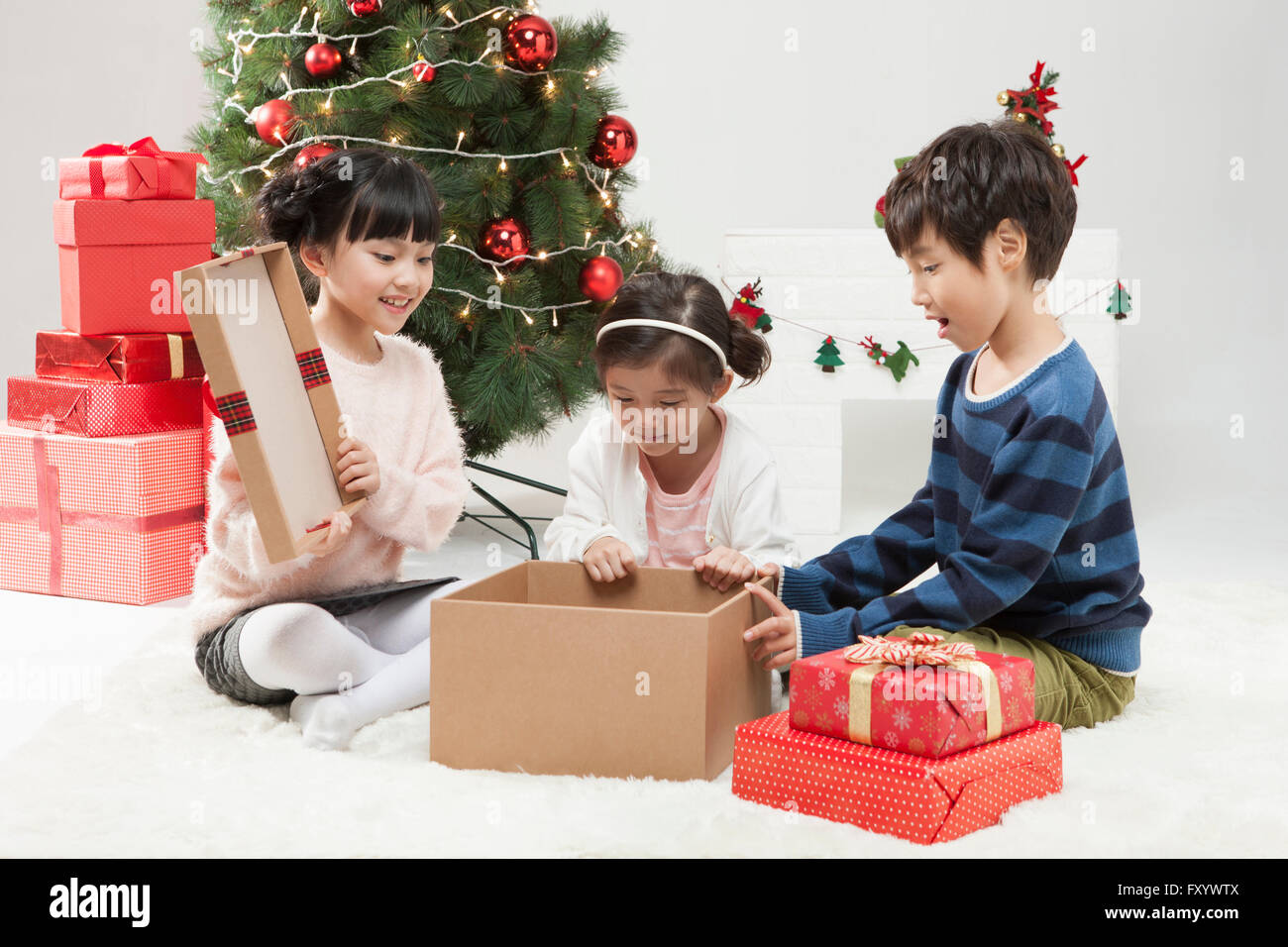 Three smiling children opening present box looking down Stock Photo