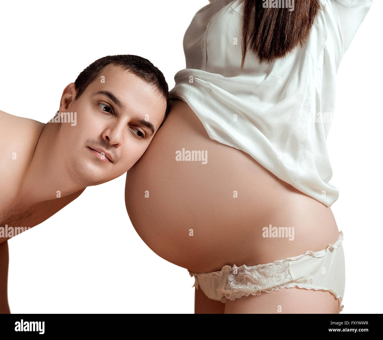 Husband listens to the tummy of his pregnant wife Stock Photo