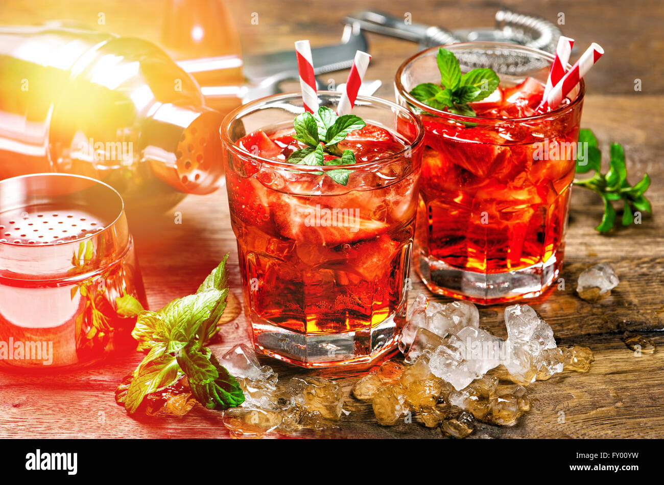 Red drink with strawberry, mint leaves, ice. Cocktail bar with party lights Stock Photo Alamy