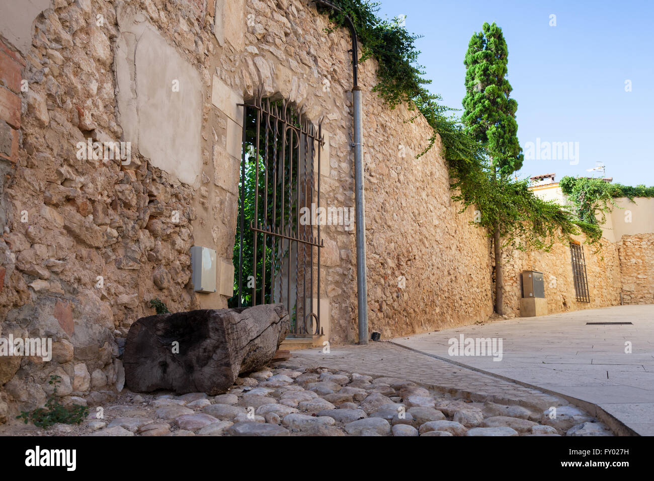 Old stone wall with closed door, street view of old Calafell town, Spain Stock Photo