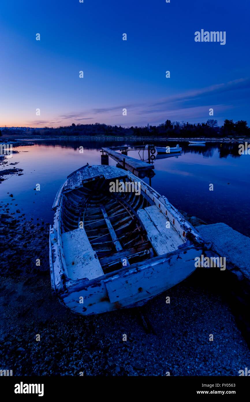 Abandoned wooden boat dusk evening night dark derelict peaceful quiet quietness Blue Bluish old damaged thrown away left and wrecked Stock Photo