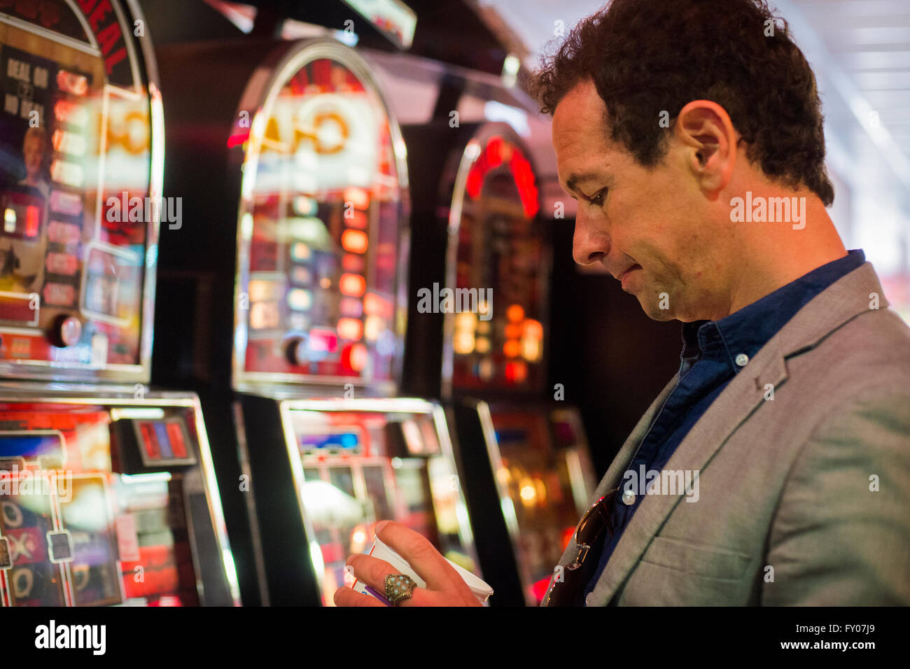 man gambling in casino with fruit machines losing money Stock Photo