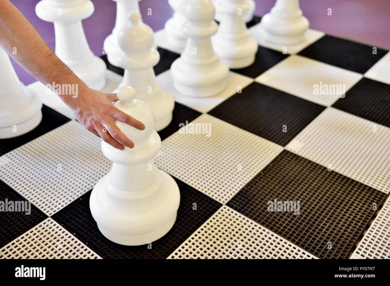 Hand moving the black pawn on a giant chess game Stock Photo