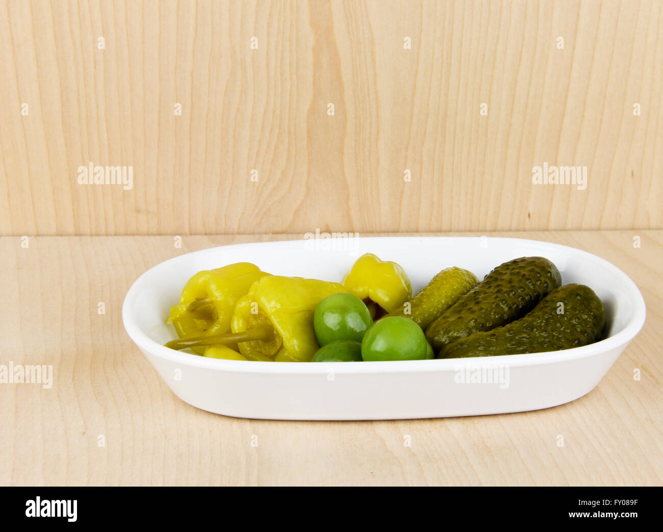 Relish dish of pickles, peppers and olives with a wooden display backgroung, Stock Photo