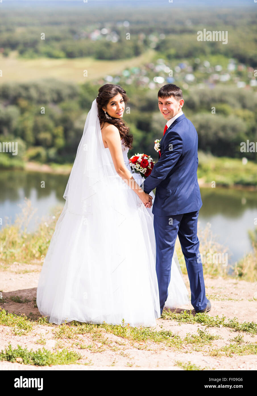 Bride and groom holding hands outdoors Stock Photo - Alamy
