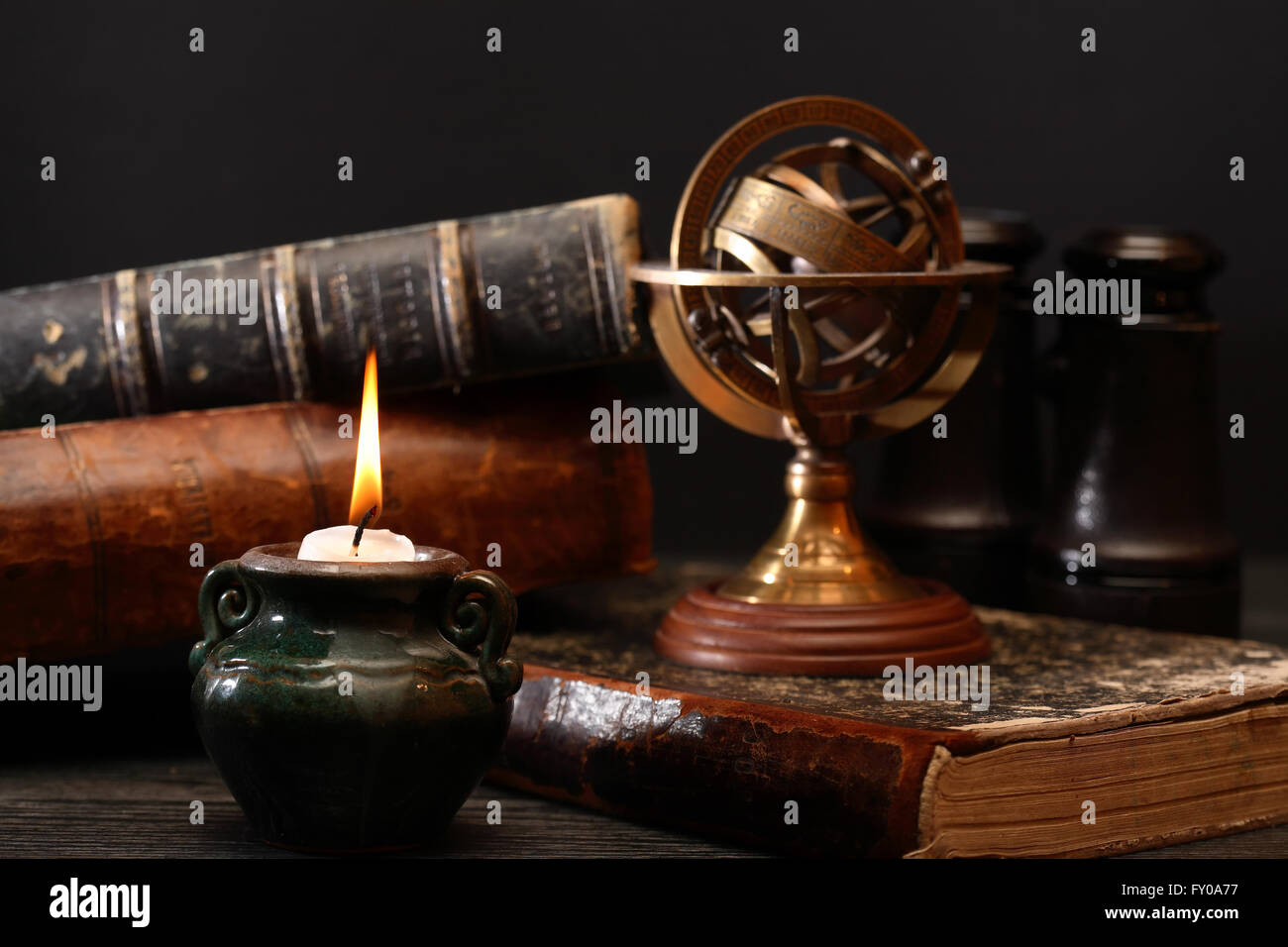 Ancient astrology. Old astrology globe and books near lighting candle Stock Photo