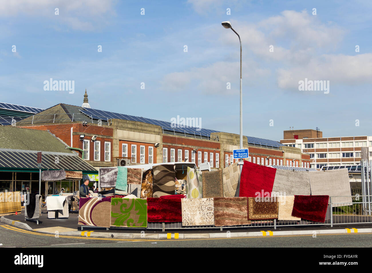 Outdoor stall selling rugs and carpets on Bolton market. The indoor market is in the background building. Stock Photo