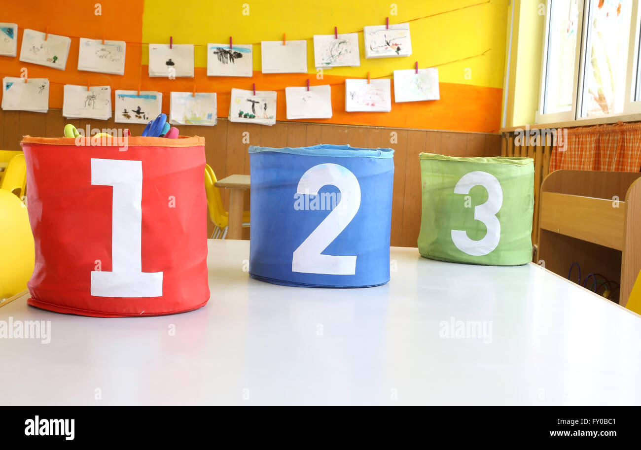 Red Green and blue jars with written one two and three on the table in the kindergarten classroom Stock Photo