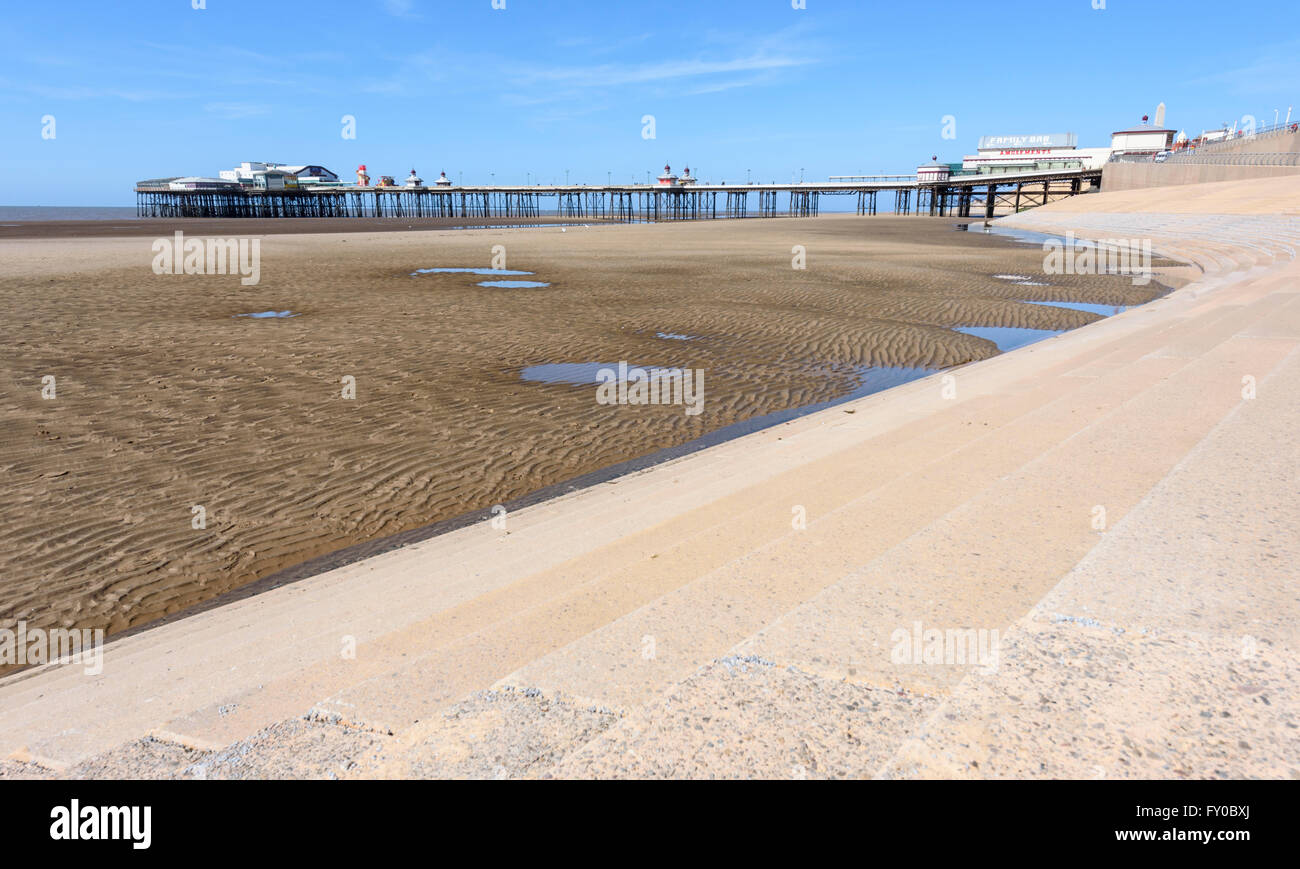 Under a bright blue sky, the view across the sandy beach to North Pier in Blackpool, Lancashire Stock Photo
