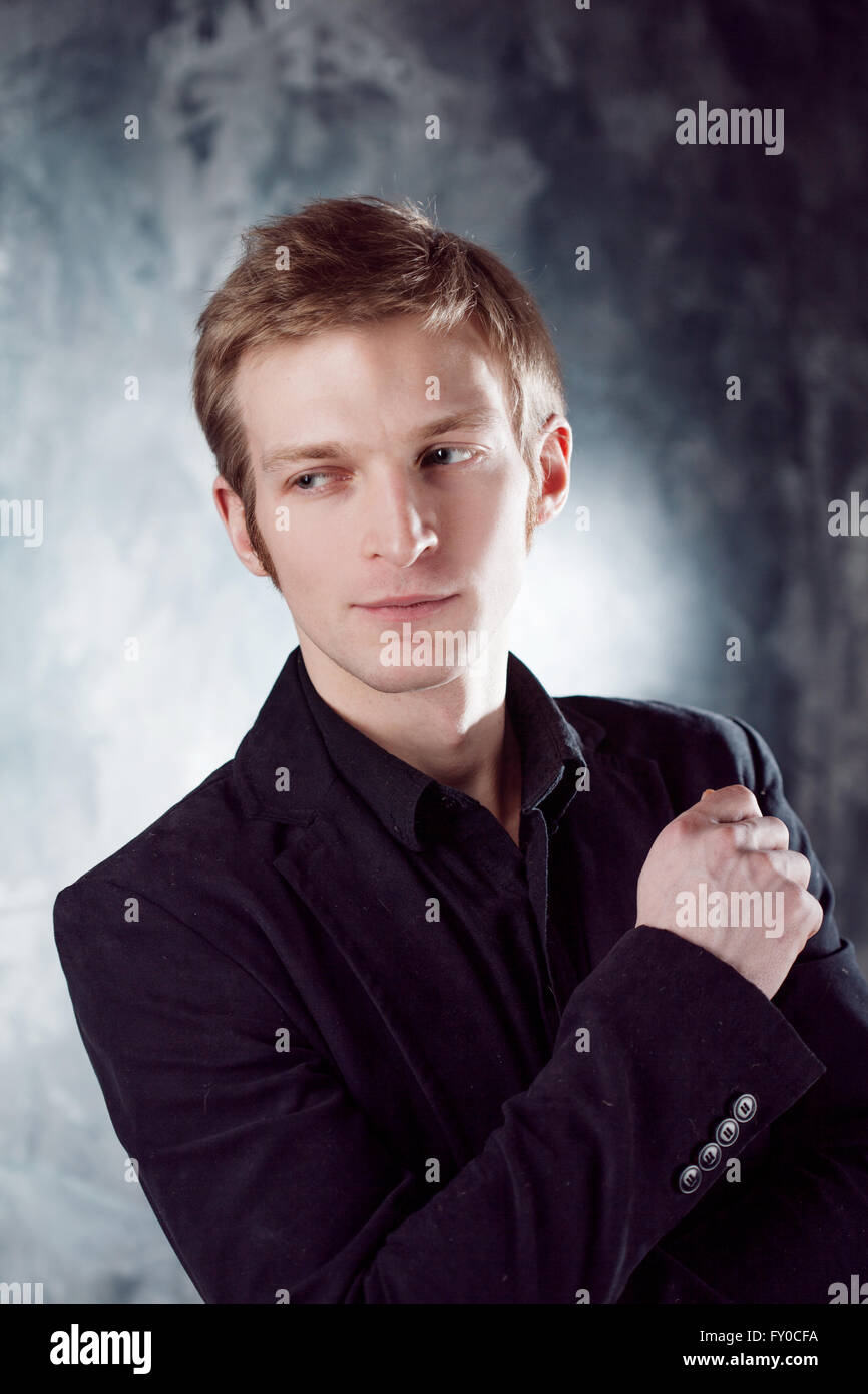 young man in black suit on textured grey background Stock Photo - Alamy