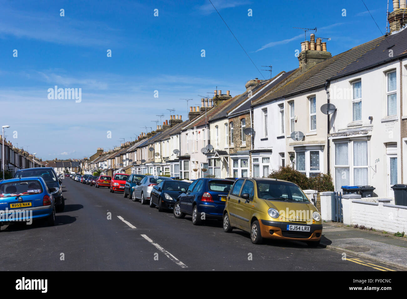 A residential street of terraced houses with on-street car parking. Stock Photo