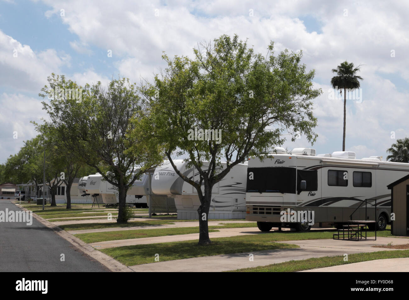 A motor home, several fifth wheel trailers and mobile homes parked in line at a mobile home/RV resort in south Texas, USA. Stock Photo