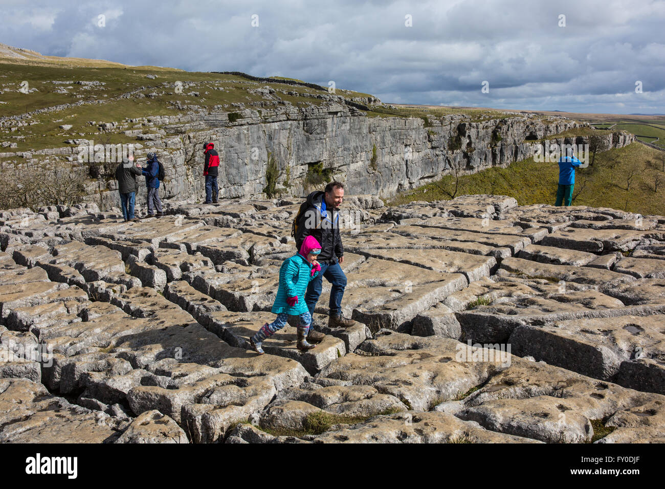 A man and his daughter navigate the limestone pavements on the cliff at Malham Cove in North Yorkshire, England Stock Photo