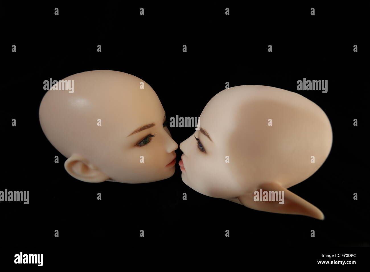 Silicone heads on black background, elf head with tongue sticking out Stock Photo