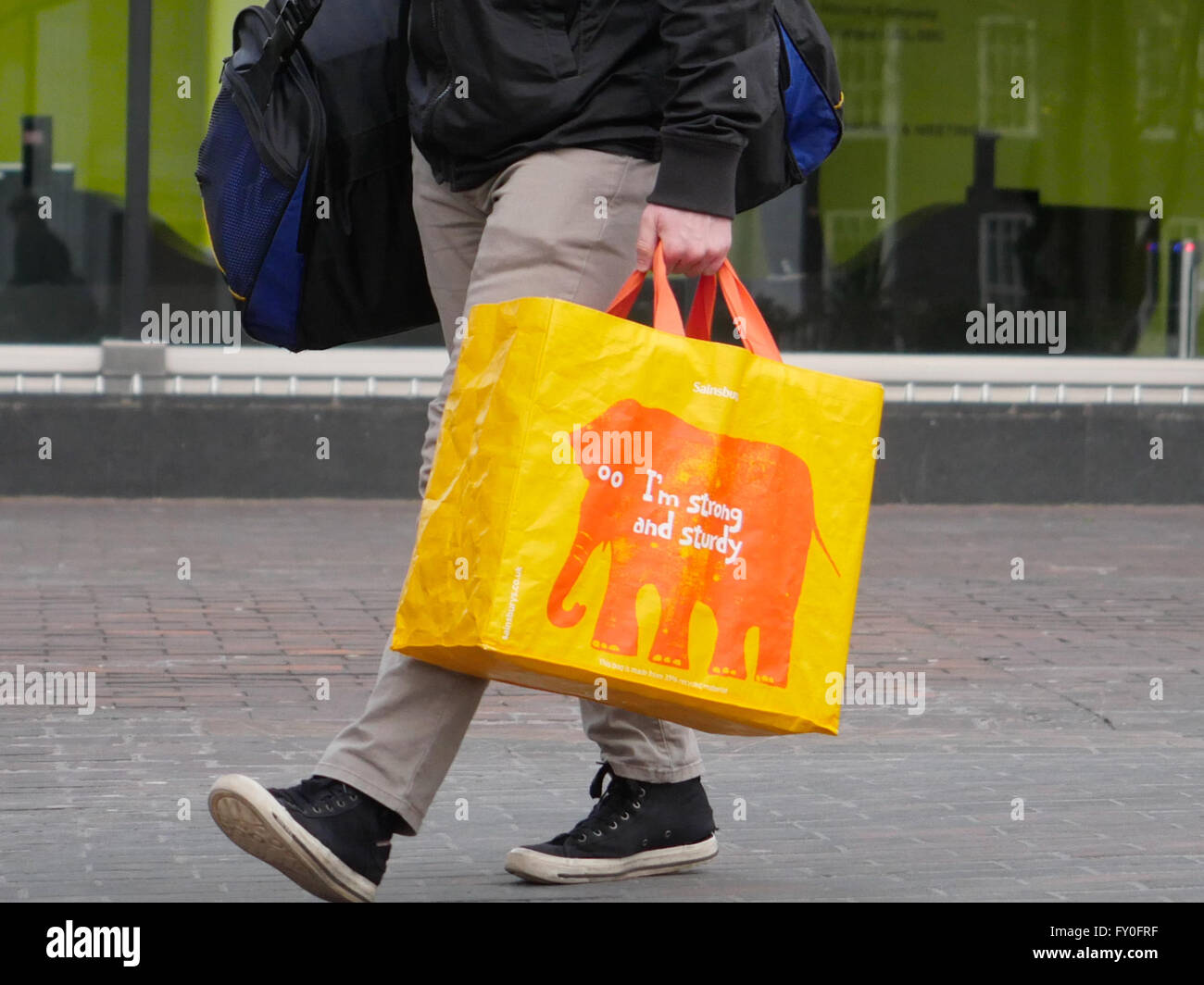 Man holding shopping bags in the street, close-up of legs Stock Photo