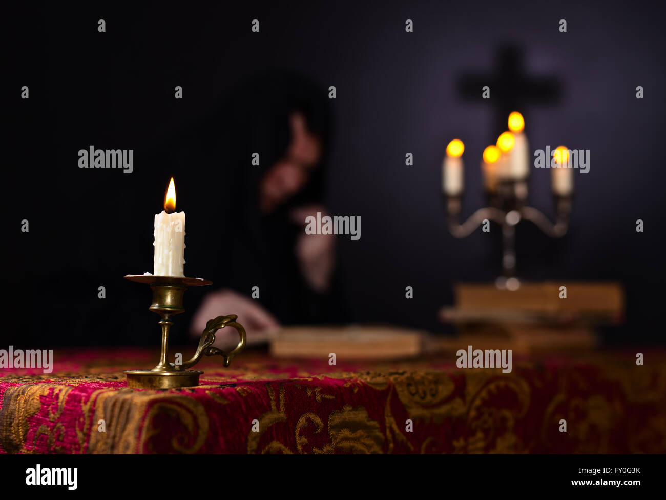 Candle on the background of the reading monk Stock Photo