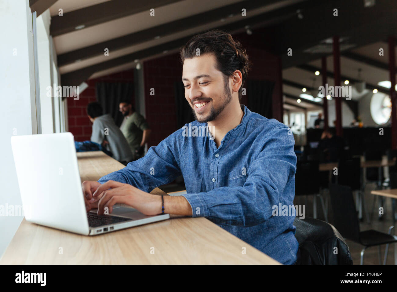 Happy man using laptop computer in office Stock Photo - Alamy