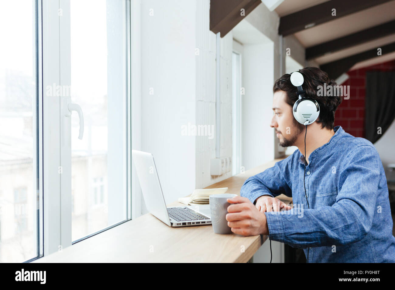 Handsome man using laptop computer with headphones in office Stock