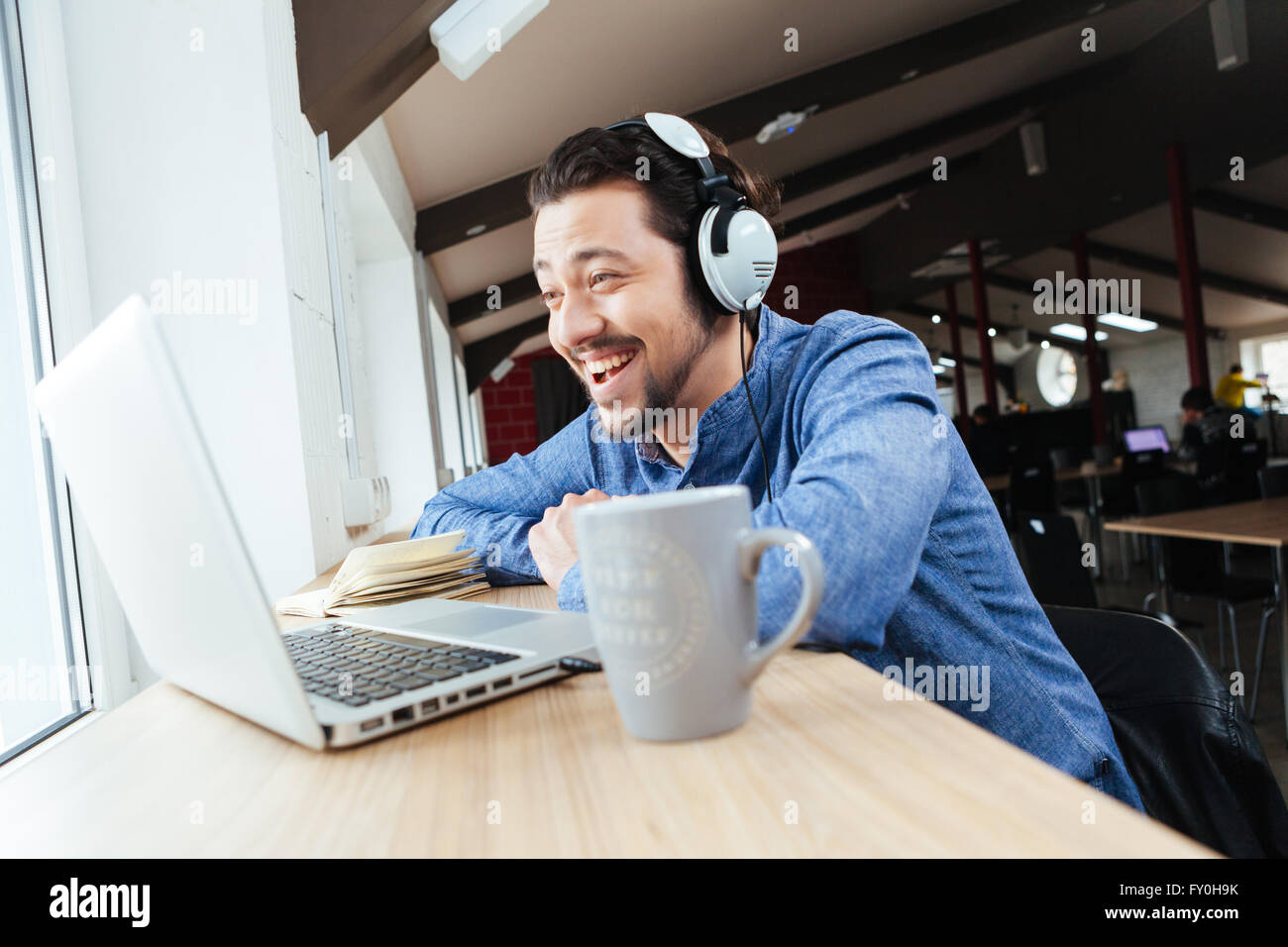 Cheerful man in headset using laptop computer in office Stock Photo - Alamy