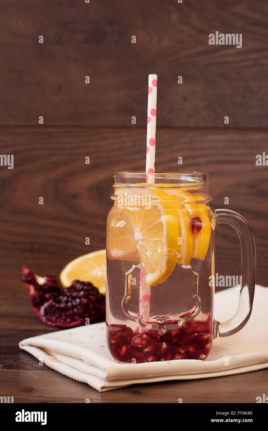 Homemade lemonade with pomegranate. Fruit water, healthy detox. Lemon and pomegranate on a wood background. Stock Photo