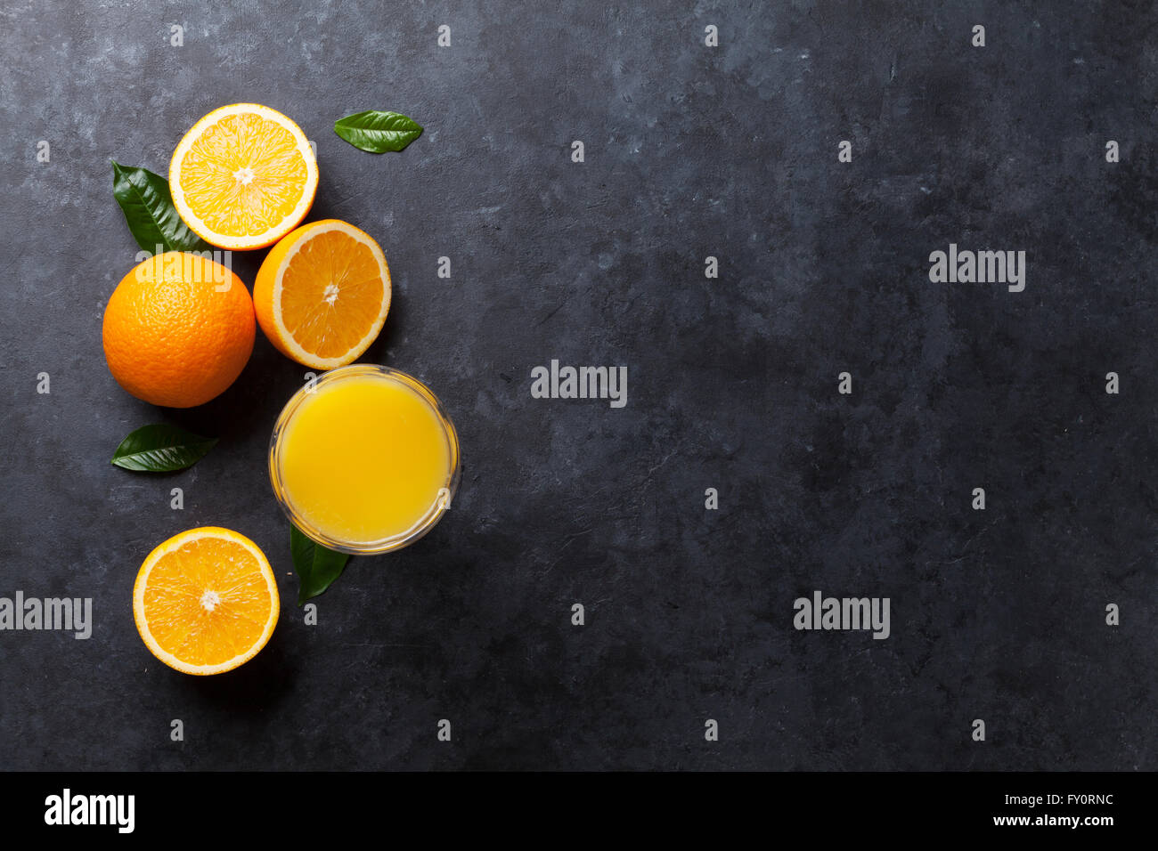 Fresh orange fruits and juice on stone table. Top view with copy space Stock Photo