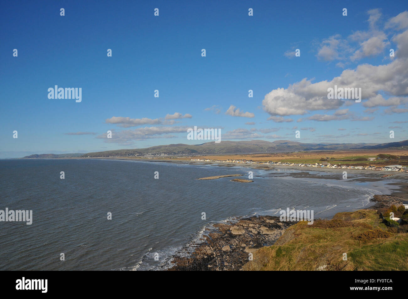 A coastal view of Borth, Ceredigion looking north on a sunny day with white clouds against a blue sky. Stock Photo