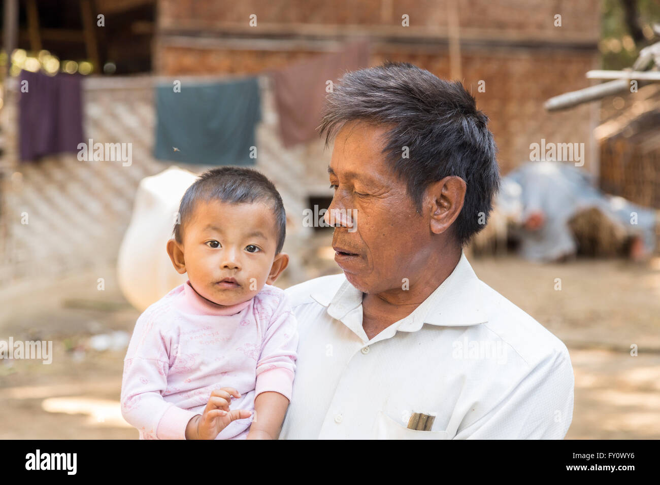 Local villager, a proud father holding his baby son in a village on the Irrawaddy River, Myanmar (Burma) Stock Photo