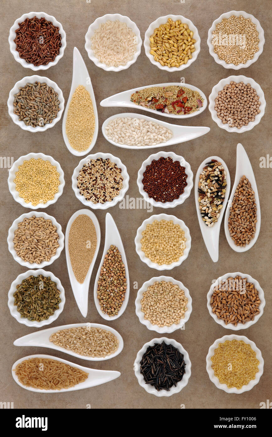 Large cereal and grain food selection in porcelain dishes over old brown paper background. Stock Photo