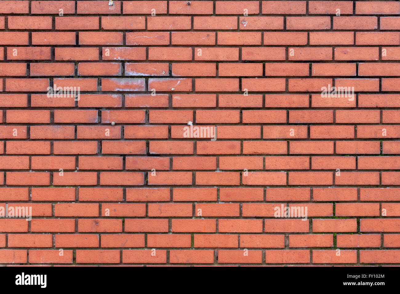 Texture of lightly weathered and stained dark red brick wall with dark