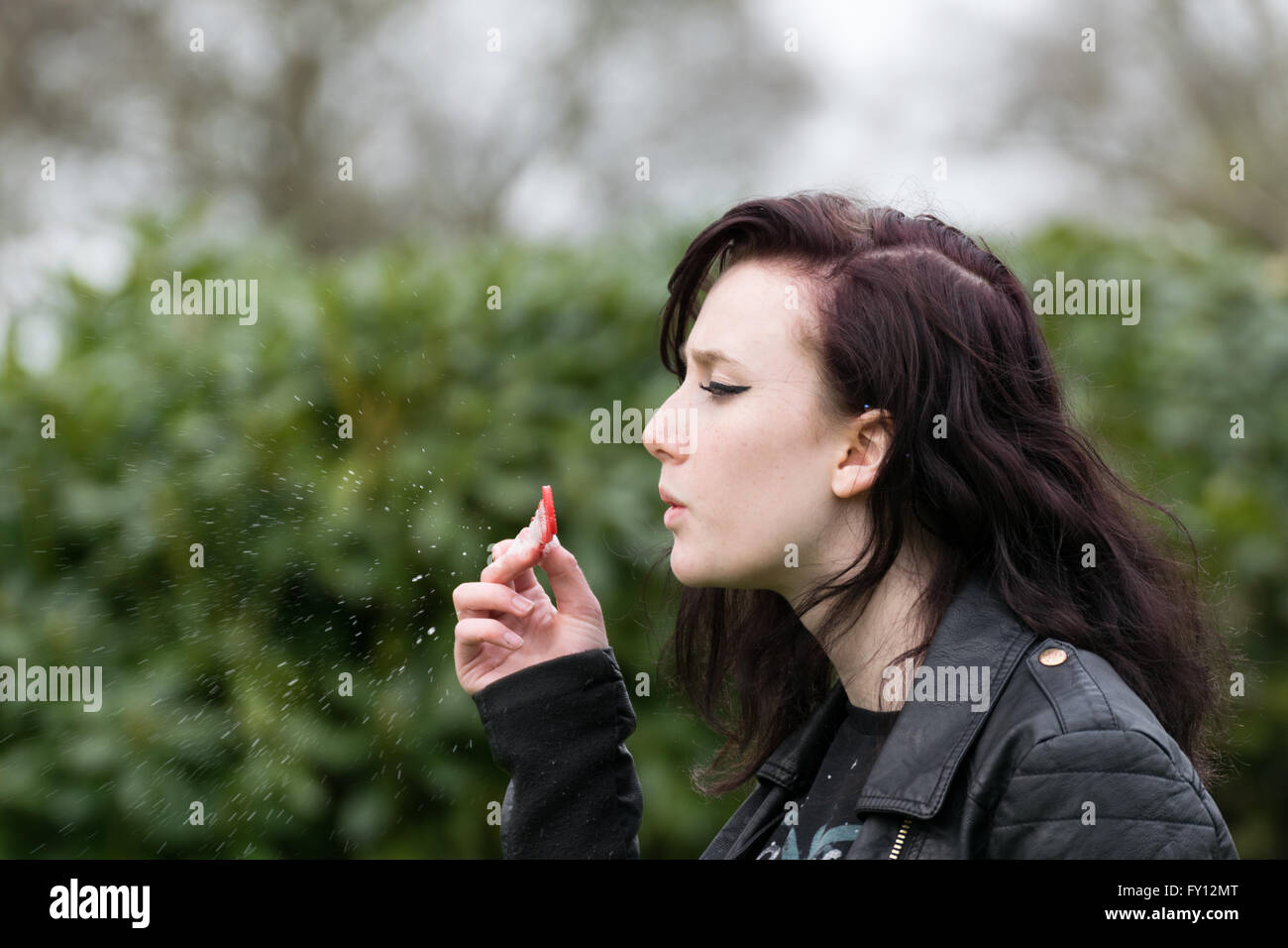 Teenager girl in leather jacket attempts to blow bubbles Stock Photo