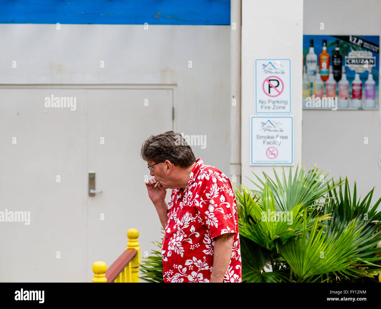 Man smoking by Smoke Free Facility sign in St Thomas Stock Photo Alamy
