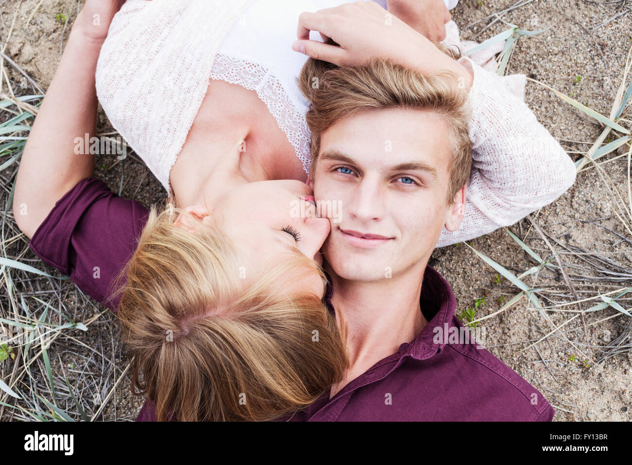 High angle view of woman kissing man while lying on field Stock Photo ...